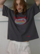 Graues T-Shirt mit rotem Aufdruck "Overdue" und weißer Spitzenhose. Modetrend, lässiger Look, Streetwear, Damenmode, urbaner Stil.