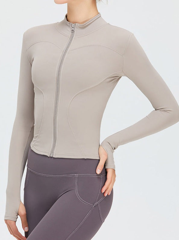 Damen-Sportjacke in Beige, langärmelig mit Reißverschluss, ideal für Fitness und Yoga. Atmungsaktives Material, figurbetontes Design.
