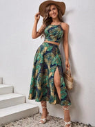 Frau in tropischem Sommerkleid mit Hut, posiert an Treppe. Perfekt für Strandmode, Damenbekleidung, Sommeroutfit, Boho-Stil.