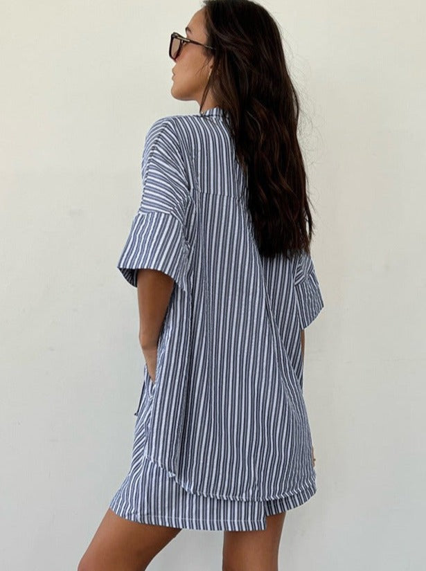 Frau in gestreiftem Hemdkleid, lässiger Sommerlook, blau-weiß, modisch, bequem, ideal für Strand oder Freizeit, trendige Damenmode.