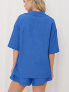 Frau in blauem Pyjama-Set aus Baumwolle, bestehend aus kurzärmligem Hemd und Shorts. Bequem, modisch, ideal für Sommernächte.
