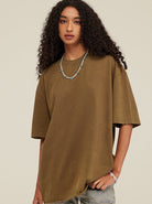 Frau in olivgrünem Oversize-T-Shirt, kombiniert mit einer türkisfarbenen Halskette. Modetrend, lässiger Stil, Damenbekleidung.