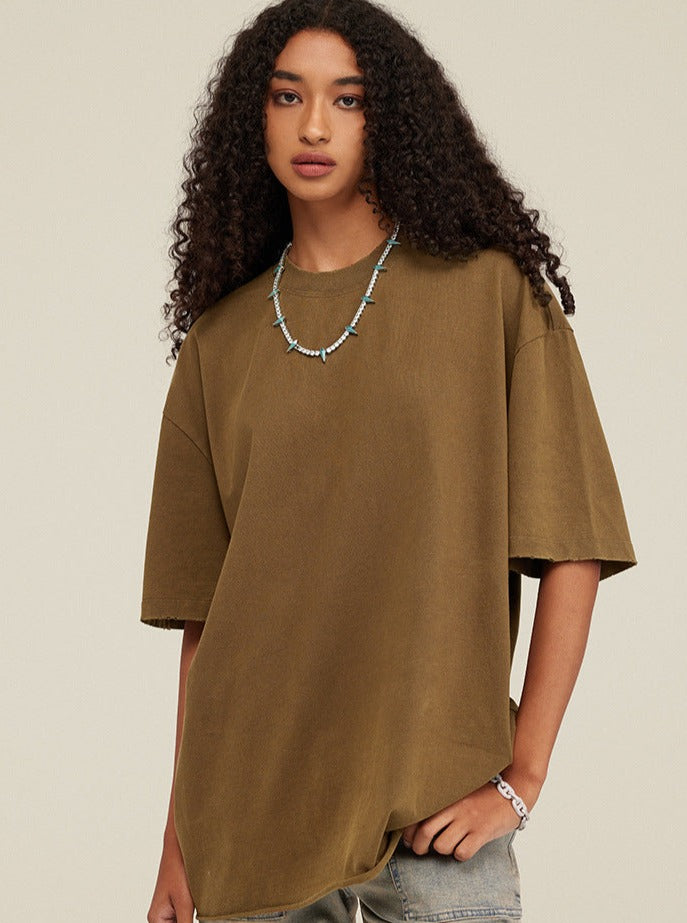 Frau in olivgrünem Oversize-T-Shirt, kombiniert mit einer türkisfarbenen Halskette. Modetrend, lässiger Stil, Damenbekleidung.
