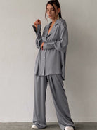 Graues Oversize-Satin-Set für Damen, bestehend aus Hemd und Hose. Modetrend, lässiger Stil, ideal für elegante Freizeitoutfits.