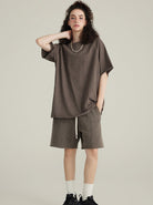 Frau in lässigem, braunem Oversize-T-Shirt und Shorts, modisch, urbaner Stil, bequeme Freizeitkleidung, ideal für Sommertrends.