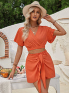Elegantes Sommeroutfit: Zweiteiliges Set in leuchtendem Orange, bestehend aus Crop-Top und Rock. Perfekt für Strandmode und Urlaubslooks.