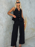 Elegantes schwarzes Damen-Outfit mit ärmelloser Weste und weiten Hosen, ideal für stilvolle Sommermode. Perfekt für trendbewusste Frauen.