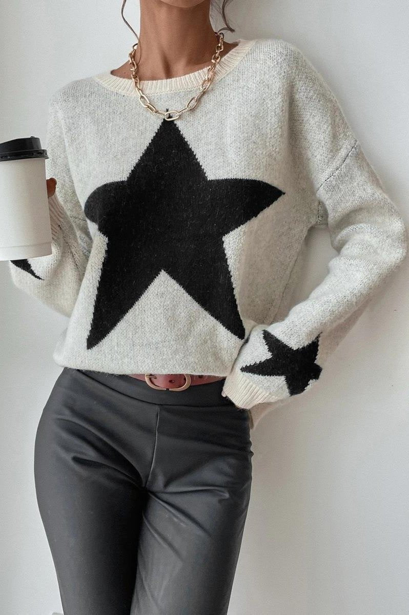 Damenpullover mit großem schwarzen Stern, kombiniert mit Lederhose. Trendige Mode, lässiger Stil, ideal für Herbst und Winter.