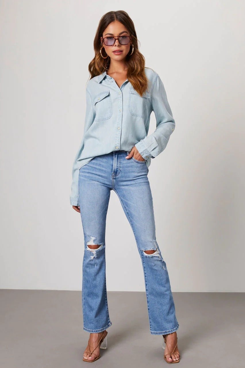 Frau in lässigem Outfit: Hellblaue Jeans mit Rissen, hellblaues Hemd, Sonnenbrille. Modetrend, Damenmode, Freizeitlook, Streetstyle.