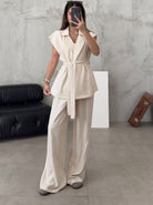 Frau in eleganter, cremefarbener Anzugweste mit Gürtel und weiter Hose, modernes Outfit, minimalistische Mode, stilvolle Damenbekleidung.