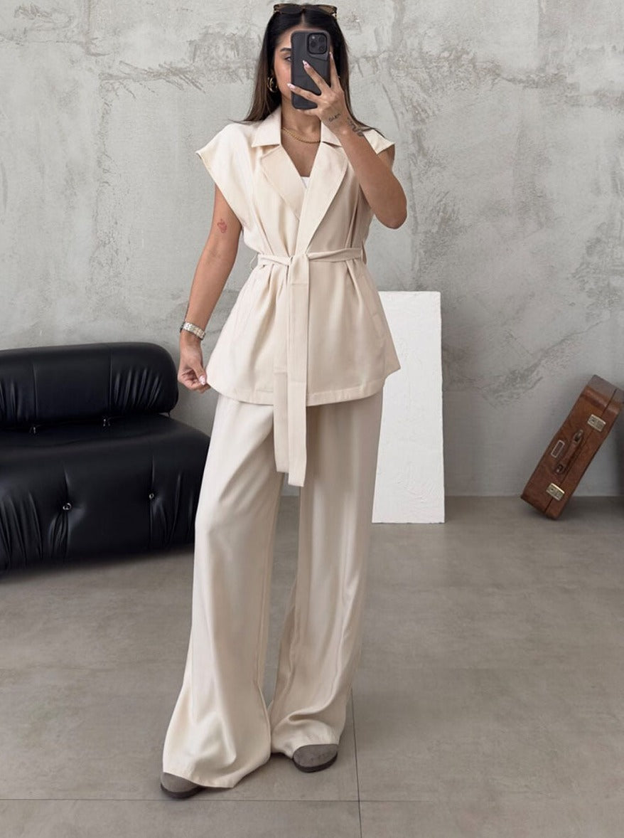 Frau in eleganter, cremefarbener Anzugweste mit Gürtel und weiter Hose, modernes Outfit, minimalistische Mode, stilvolle Damenbekleidung.