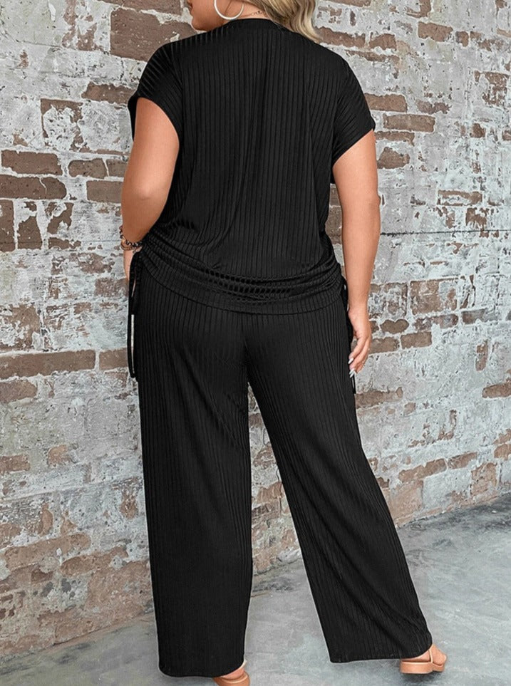 Damen-Set aus schwarzem, geripptem Stoff, bestehend aus T-Shirt und Hose. Bequemes Freizeit-Outfit für Plus-Size-Mode, ideal für den Alltag.