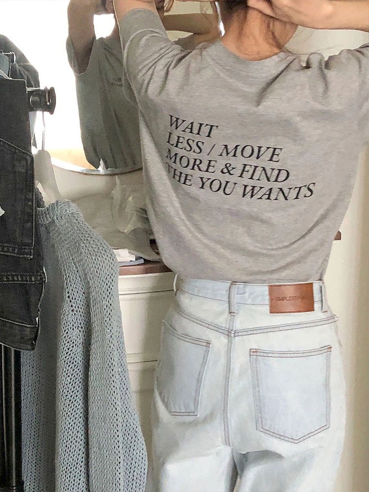 Graues T-Shirt mit inspirierendem Zitat, kombiniert mit hellblauen Jeans. Perfekt für lässige Mode und Streetwear-Trends.