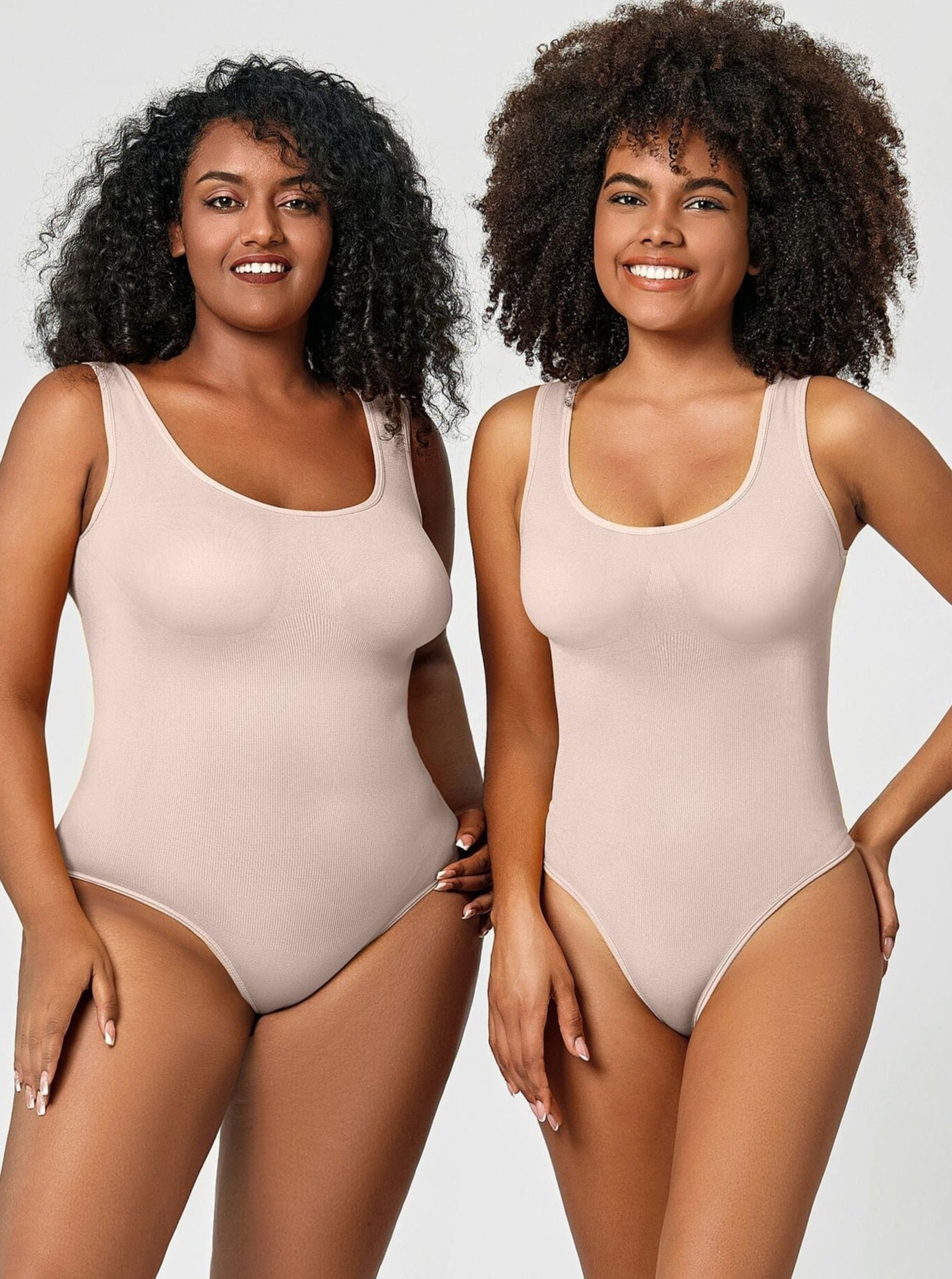 Zwei Frauen in hautfarbenen Bodysuits, lächelnd, vor neutralem Hintergrund. Mode, Damenbekleidung, Bodysuit, Komfort, Eleganz.