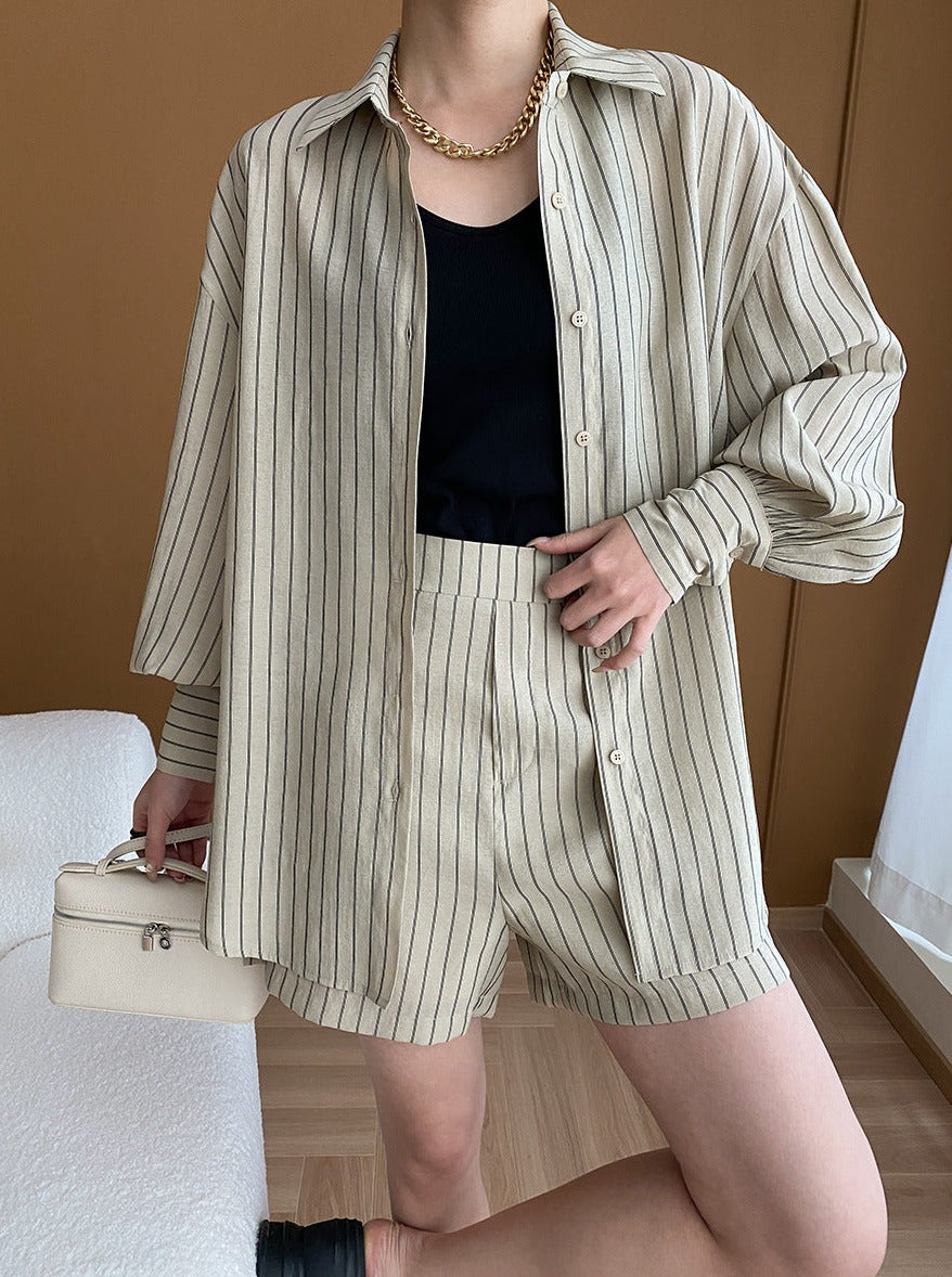 Gestreifter, beigefarbener Damen-Zweiteiler mit Hemd und Shorts, kombiniert mit schwarzem Top und goldener Kette. Elegante, lässige Mode.