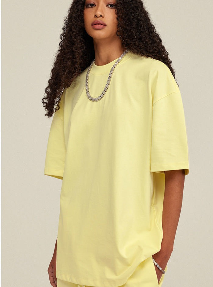 Gelbes Oversize-T-Shirt für Damen, kombiniert mit einer silbernen Halskette. Modetrend 2023, lässiger Stil, bequeme Passform, Streetwear.