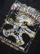 Schwarzes T-Shirt mit auffälligem, buntem Grafikdruck eines stilisierten Lebkuchenmanns, umgeben von Stacheldraht. Streetwear, urban, modisch.