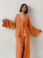 Frau in orangefarbenem Kimono-Set mit weitem Schnitt, minimalistisches Design, modisch, eleganter Look, ideal für stilvolle Anlässe.