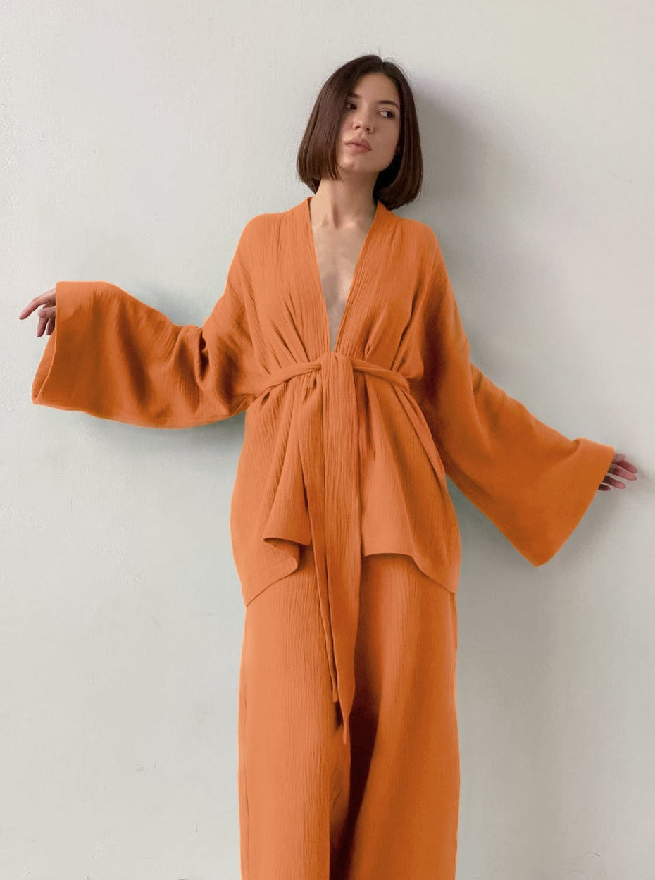 Frau in orangefarbenem Kimono-Set mit weitem Schnitt, minimalistisches Design, modisch, eleganter Look, ideal für stilvolle Anlässe.