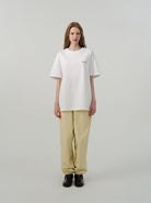 Damenmode: Weißes Oversize-T-Shirt und beige Hose, minimalistisch, lässig, modern. Perfekt für trendige, bequeme Alltagsoutfits.