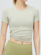 Damen-Sportshirt in Beige, kurzärmelig, atmungsaktiv, ideal für Fitness und Yoga. Hochwertige Materialien, figurbetontes Design.