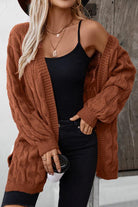 Frau in braunem Strickcardigan, schwarzem Top und Jeans, hält Kaffeebecher. Herbstmode, lässiger Look, Strickjacke, Damenbekleidung.