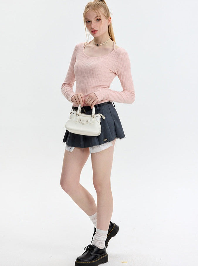 Junge Frau in rosa Pullover und grauem Rock, hält weiße Handtasche. Modetrend, Damenmode, stilvolle Kleidung, lässiger Look, Streetstyle.