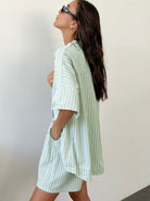Frau in gestreiftem, mintgrünem Hemdkleid, seitlich posierend. Sommermode, lässiger Stil, trendiges Outfit, Damenbekleidung, modische Streifen.