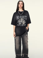 Schwarzes Oversize-T-Shirt mit "No Regrets"-Aufdruck, kombiniert mit lässigen, zerrissenen Jeans. Perfekt für Streetwear und urbanen Stil.