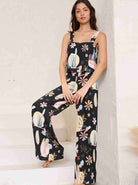 Frau in stilvollem, schwarzem Jumpsuit mit buntem Blumenmuster, ideal für Sommermode. Perfekt für trendige, lässige Outfits und Freizeitkleidung.