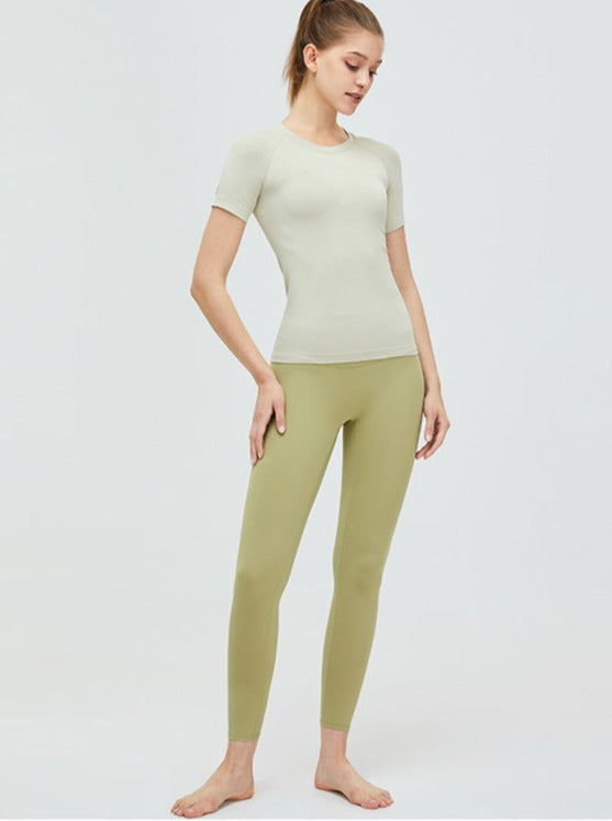 Frau in nahtlosem, hellgrünem Sportoutfit. Perfekt für Yoga und Fitness. Atmungsaktive Leggings und T-Shirt für maximalen Komfort.