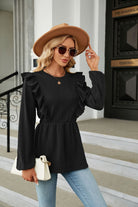 Elegante Frau mit Sonnenbrille und Hut, trägt schwarze Rüschenbluse und Jeans, hält weiße Handtasche. Modetrends, Damenmode, stilvoller Look.