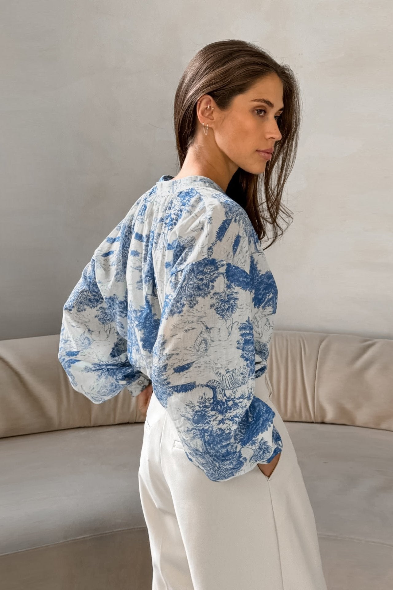Frau in eleganter, blauer Print-Bluse und weißen Hosen. Modetrend, Damenmode, stilvolle Kleidung, lässiger Chic, zeitloses Design.