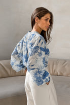 Frau in eleganter, blauer Print-Bluse und weißen Hosen. Modetrend, Damenmode, stilvolle Kleidung, lässiger Chic, zeitloses Design.