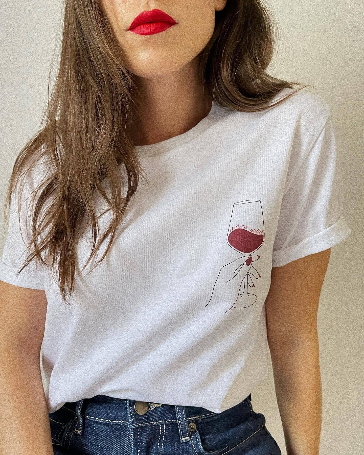 Frau in weißem T-Shirt mit Weinglas-Design, rote Lippen, lange braune Haare. Modetrend, lässiger Stil, Damenmode, T-Shirt mit Print.