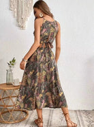 Frau in einem tropischen Sommerkleid mit Blumenmuster, stehend vor weißer Wand. Perfekt für Strandmode, Boho-Stil, lässige Sommeroutfits.