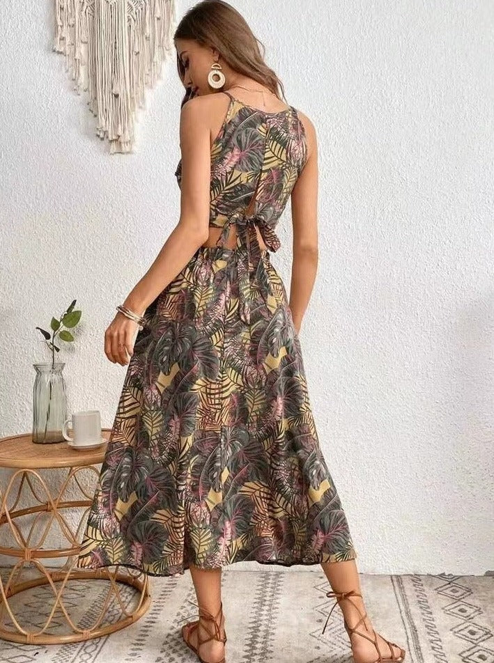 Frau in einem tropischen Sommerkleid mit Blumenmuster, stehend vor weißer Wand. Perfekt für Strandmode, Boho-Stil, lässige Sommeroutfits.