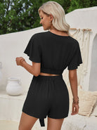 Frau in schwarzem Sommer-Set, bestehend aus Crop-Top und Shorts, im Freien. Modetrend, Damenbekleidung, lässiger Stil, Sommermode.