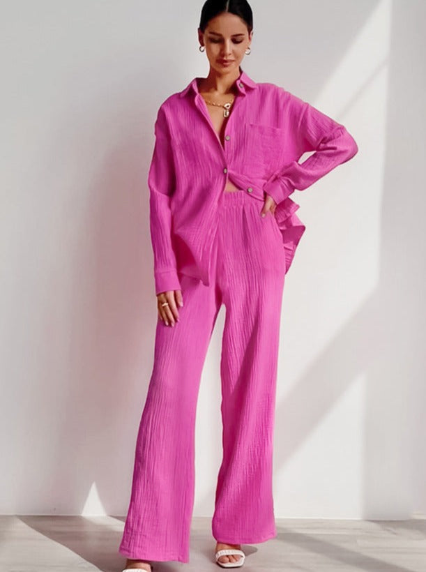 Frau in pinkem Hosenanzug, bestehend aus lockerem Hemd und weiten Hosen. Modetrend, Damenmode, eleganter Look, Sommeroutfit, stilvoll.
