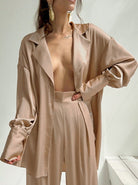 Elegante Damenbluse in Beige, oversized und aus Satin, kombiniert mit passender Hose. Perfekt für stilvolle, moderne Outfits und Mode-Trends.