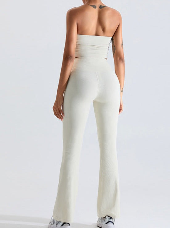 Frau in eleganter, weißer, schulterfreier Jumpsuit, Rückansicht. Modetrend, Damenbekleidung, stilvoll, modern, bequem, Sommeroutfit.