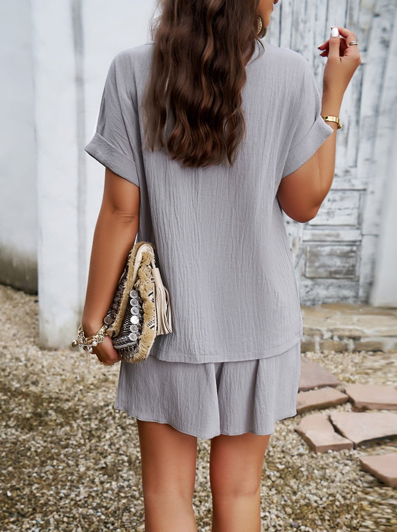 Frau in grauem Sommerkleid, hält stilvolle Clutch. Modetrend, Damenmode, Sommeroutfit, lässiger Look, elegantes Design, Accessoires.