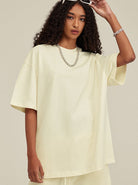 Frau in cremefarbenem Oversize-T-Shirt, modisch, lässig, mit Kette. Perfekt für Streetwear, Sommermode, trendige Damenbekleidung.