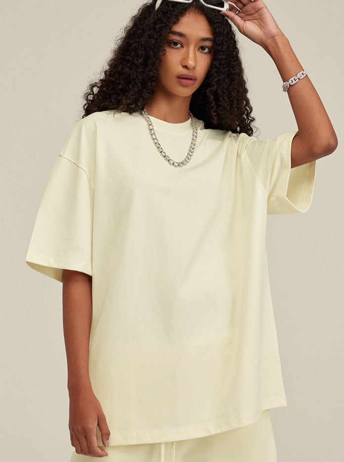 Frau in cremefarbenem Oversize-T-Shirt, modisch, lässig, mit Kette. Perfekt für Streetwear, Sommermode, trendige Damenbekleidung.