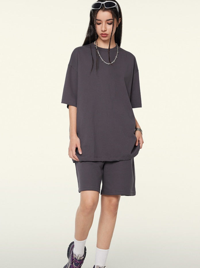 Frau in grauem Oversize-T-Shirt und Shorts, modisch, lässig, Streetwear, mit weißen Sneakers und Sonnenbrille, urbaner Stil, trendig.