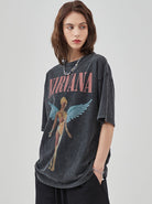 Frau trägt ein schwarzes Nirvana-T-Shirt mit Engelsmotiv. Modetrend, lässiger Stil, Vintage-Bandshirt, Damenmode, Streetwear.