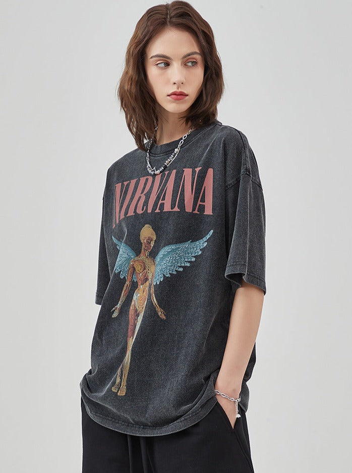 Frau trägt ein schwarzes Nirvana-T-Shirt mit Engelsmotiv. Modetrend, lässiger Stil, Vintage-Bandshirt, Damenmode, Streetwear.