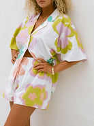 Frau in geblümtem Sommer-Set aus Hemd und Shorts, pastellfarben, modisch, lässig, ideal für warme Tage, trendige Damenmode, bequem und stilvoll.