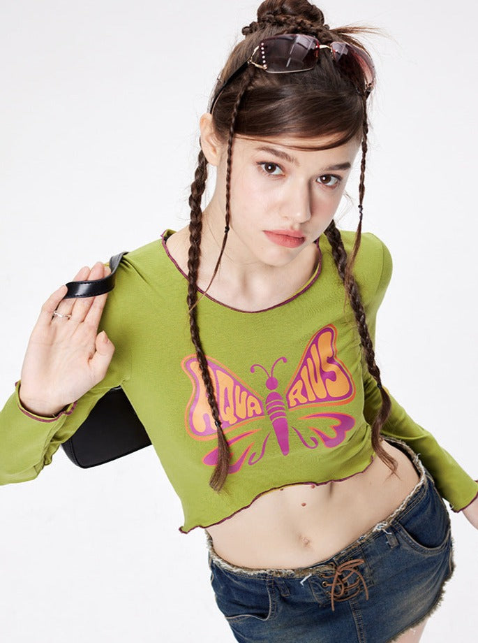 Junge Frau in grünem Crop-Top mit Schmetterlingsmotiv und Jeansshorts, modisch, trendig, Streetwear, lässiger Stil, Sommermode.