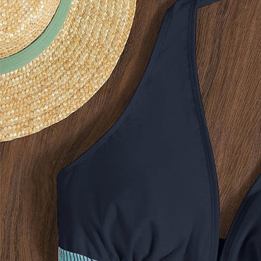 Strohhut und schwarzer Badeanzug auf Holzhintergrund. Sommermode, Strandaccessoires, stilvoller Look für Urlaub und Freizeit.